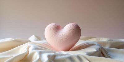 A textured pink heart sculpture resting on a soft surface with a subtle gradient background photo