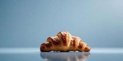 Croissant on reflective surface with soft blue background and ample copy space photo