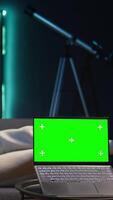 Vertical African american freelancer laying on the couch with music next to mockup display on pc, feeling happy with flexible work schedule at home. Young adult uses his tablet relaxing on sofa. Camera B. video