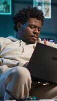 Vertical Black remote worker suffers from diabetes and uses glucometer at home, checking his sugar levels with a blood sample. Young adult using an insulin pen for glucose measurement. Camera A. video