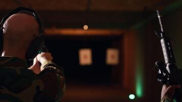 Team of army soldiers practicing with firearms in shooting range to increase firing accuracy. Military units in shooting gallery using pistols and rifles to engage targets at extended range, camera B video