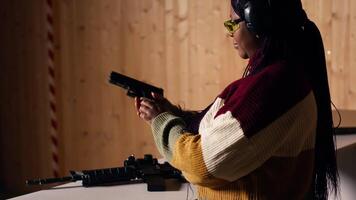 Cheerful woman in shooting range trying out new gun model before committing to purchase. Happy person in firing range learning how to operate new weapon safely during self defense training, camera B video