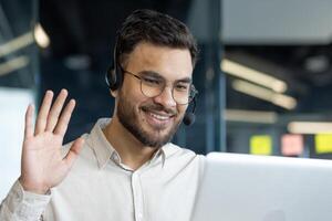 Man with headset and laptop inside office. Online customer support worker talking using call. Businessman close up on business meeting conference with colleagues. photo