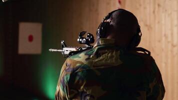 Portrait of happy military personnel using tactical operations equipment, shooting assault rifle. Smiling man in firing range preparing for mission, practicing with semiautomatic weapon, camera B video