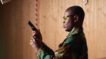 Soldier in shooting range reloads pistol, shooting target, celebrating after achieving perfect accuracy. Military unit in firing range practices with weapon, cheering after hitting bullseye, camera B video