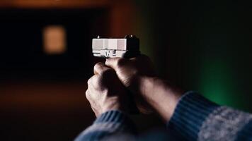 Shooting range client shoots with pistol, engaging targets at extended range. African american man at shooting ground firing lethal fire weapon, wearing protection equipment, camera B close up video