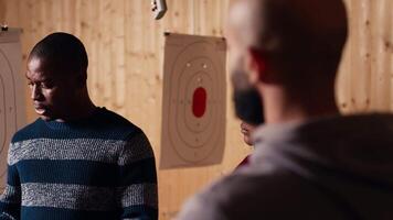 Shooting range safety officer demonstrating how to safely reload pistol to customers based on industry regulations. Firing range staff member teaching proper handgun handling, camera B video