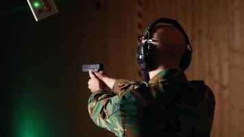 Cheerful army unit in firing range shooting targets with pistol pleased after achieving positive result. Excited soldier training with weapon thrilled after accurately hitting bullseye, camera B video