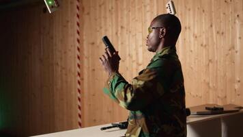 Soldier in shooting range reloads pistol, shooting target, celebrating after achieving perfect accuracy. Military unit in firing range practices with weapon, cheering after hitting bullseye, camera A video
