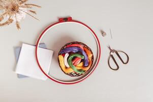 Basket with colored floss, canvas, embroidery hoop and scissors on gray background top view photo