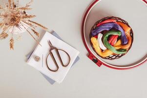 Basket with colored floss and canvas for embroidery on a gray background top view photo