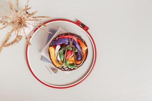 Scissors on basket with colored embroidery threads in hoops on gray background top view photo