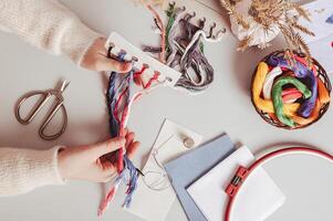 Female hands holding a set of colored embroidery floss on a work table top view photo
