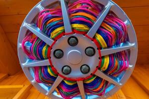 Unique wheel cover featuring vibrant colored strands in a decorative pattern at a craft market photo