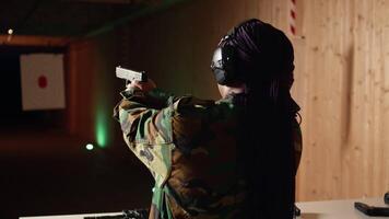 Smiling woman in firing range doing recreational shooting activity with firearm, hitting bullseyes. Happy person in shooting gallery training with handgun, developing muscle memory, camera A video