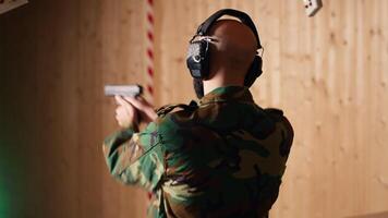 Happy military personnel in firing range shoots targets with handgun, satisfied after achieving positive result. Joyous soldier training with firearm exults after accurately hitting bullseye, camera B video