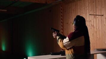 Cheerful woman in shooting range trying out new gun model before committing to purchase. Happy person in firing range learning how to operate new weapon safely during self defense training, camera A video