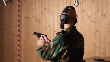 Army soldier in shooting range reloads pistol, shooting target, testing accuracy, looking at results. Military man in firing range practices with weapon, checking to see if he shot bullseye, camera B video