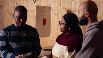 Shooting gallery safety officer demonstrating how to safely reload pistol and gun to clients, supervising range activities. Firing range expert teaching proper weapon handling and usage, camera B video