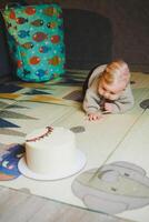 A blond baby crawls on the floor at home and wants to eat a sweet cake. Child development. A boy learns to crawl. photo