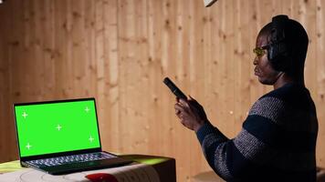 Chroma key notebook and shooting range customer reloading pistol, shooting targets. Isolated screen laptop next to man at shooting ground facility loading pistol, wearing protection goggles, camera B video