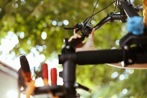 Close-up of person using expert work tools to adjust and secure bike handlebar in yard. Detailed shot of caucasian male arm fixing bicycle component for yearly maintenance. photo