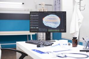 Clinic office with desktop pc displaying brain imaging and scans emphasizing on technology for neurological analysis. Nobody is present allowing focus on medical files screen data and equipment. photo