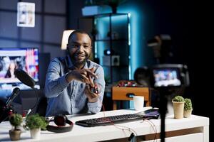 African american technology internet star filming review of newly released USB wired RGB lights mouse. Man giving audience feedback about computer peripheral power, doing endorsement photo