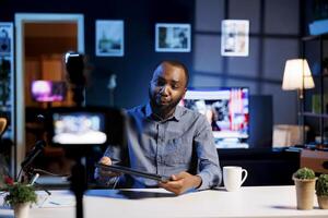 African american influencer filming tech tutorial on how to do maintenance on laptop, presenting internal parts. Technology internet show host teaching subscribers to fix notebook device photo