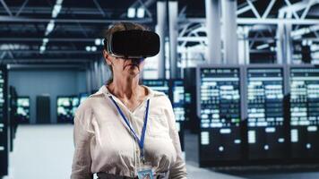 Older computer scientist in modern server hub wearing virtual reality headset, performing racks maintenance. Licensed professional using vr glasses in high tech workplace to do checkup on hardware photo