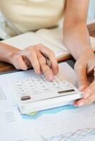 Hands using a calculator on financial documents with graphs, ideal for business, finance, and accounting themes. photo