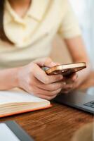 Hands holding a smartphone over a notebook and laptop, capturing a casual work or study environment. photo