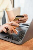 Hands holding a credit card and typing on a laptop, illustrating online shopping or e-commerce in a comfortable setting. photo