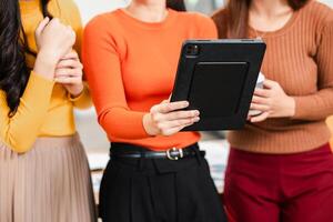 Three women using a tablet for collaboration in a modern office environment, showcasing teamwork and technology. photo