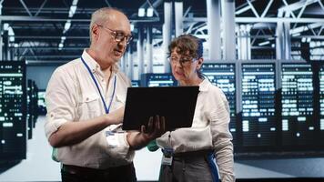 IT team in data center using laptop to monitor energy efficient supercomputers. Server hub using renewable sources employed to minimize consumption and reduce overall facility carbon footprint photo