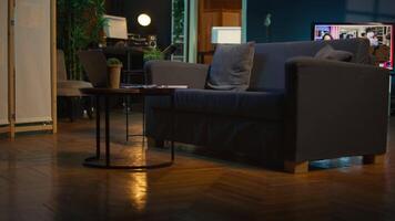 elegante vacío Departamento desván con un cómodo sofá y inteligente televisión en el vivo habitación, moderno espacio con decoraciones y miedoso neón luces. estudio con un café mesa y hogar teatro configuración. video