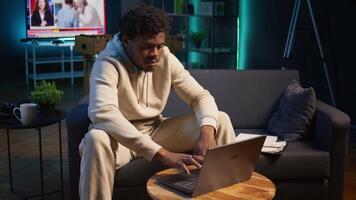 African american male freelancer managing creative projects remotely in his loft, working on a new novel or script for his gig. Man focusing on writing and editing creation, telework. Camera B. video