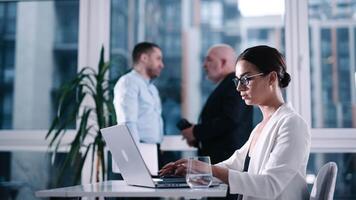 Young smiling American mentor explaining to serious coworker project strategy. Diverse startup coworkers students girl and guy talking discussing working in modern office using laptop video
