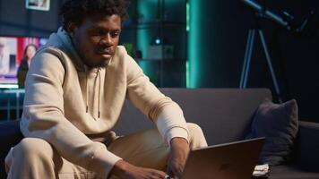 zuversichtlich jung Mann lösen Täglich Aufgaben auf ein freiberuflich Plattform beim heim, antworten E-Mails und Multitasking. Person bleiben in Verbindung gebracht und genießen das Flexibilität von Arbeiten entfernt. Kamera b. video