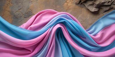Flowing pink and blue fabric creating a gradient effect on textured background photo