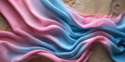 Flowing pink and blue fabric creating a gradient effect on textured background. photo