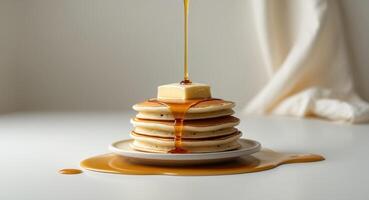 A stack of fluffy pancakes topped with butter and syrup drizzling down photo