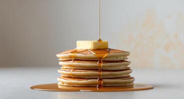 A stack of fluffy pancakes topped with butter and syrup drizzling down. photo