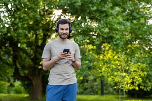 Man engages in active fitness in park setting using smartphone and headphones. Surrounded by greenery, enjoying technology and tranquility. Captures essence of modern exercise and connection photo