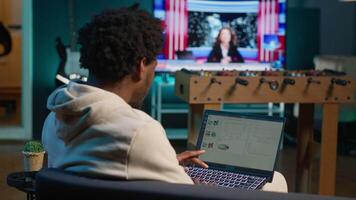 African american person working from home and checking statistical data on laptop screen, analyzing financial graphs. Teleworker in the living room comparing business revenue numbers. Camera A. video