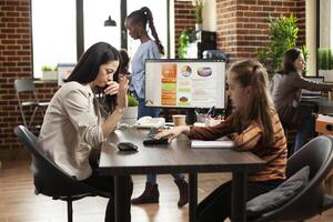 Working mom reviewing market strategy on desktop pc and annoyed by daughter interrupting at desk in startup office. Little girl plays with keyboard on table as woman is trying to work on computer. photo