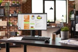 Vacant brick wall workspace with desktop monitor, notebooks and financial paperwork on table. Business analytics data displayed on computer screen and documents on desk are prepared for presentation. photo