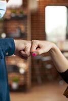 Business partners in office share fist bump, symbolizing teamwork and mutual support. Caucasian coworkers doing hand gestures that highlights strong partnership in startup company. photo