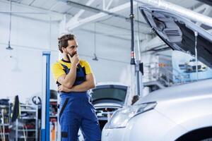 Technician in repair shop using augmented reality holograms to check car performance indicators during checkup. Precise garage employee using futuristic AR technology to examine broken vehicle photo