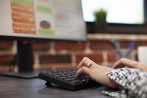Closeup of hands typing on keyboard in office , working at a desk in startup company. Selective focus on the fingers inputting project data on digital device, productivity in business environment. photo